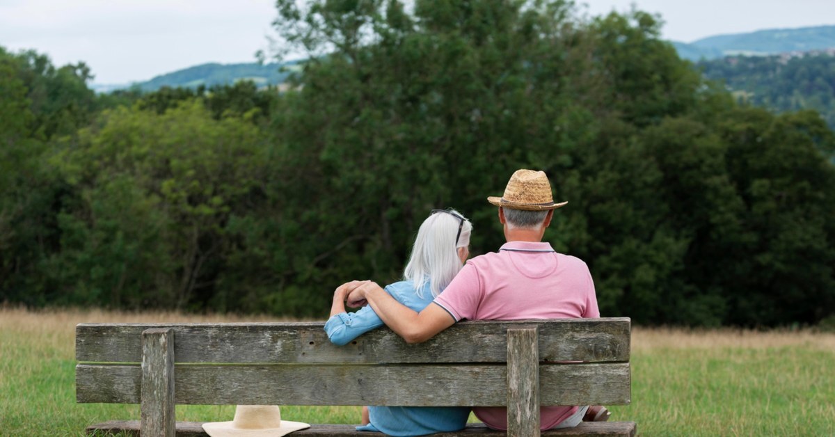 Man and Women sitting on bench enjoying a nice day.